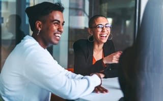 Two people smiling and laughing together in a conference room.