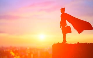 silhouette of super business woman wearing a superhero cape standing on a mountain