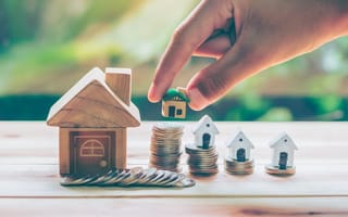 Tiny houses being placed on top of stacks of coins