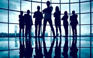 Business team standing against window with leader in front