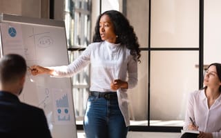 A female leader making a whiteboard presentation for employees in office