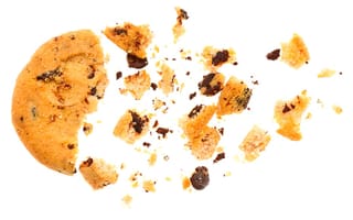 Broken chocolate chip cookie and crumbs on a white background