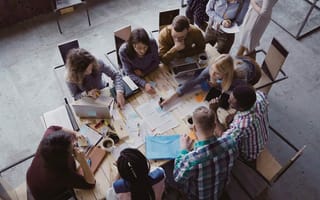 Aerial view of mixed race business team sitting at the table at loft office and working.