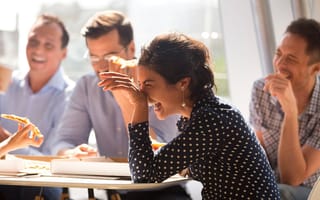 Coworkers laughing and eating pizza together in the office