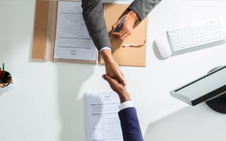 High angle view of businessmen shaking hands over a white desk