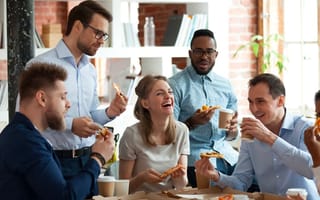 Colleagues talking, laughing and sharing a pizza in the office