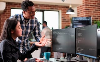 two engineers looking at a computer monitor using a software progaming application