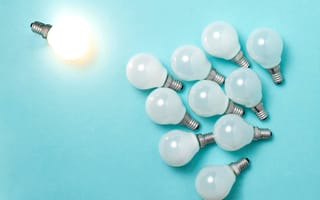 One light bulb outstanding, glowing above a bunch of unlit light bulbs
