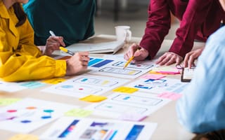 Close up ux developer and ui designer brainstorming about mobile app interface wireframe design on table