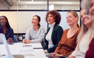 Businesswomen In Modern Office Listening To Presentation By Colleague