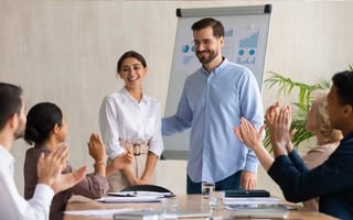 male leader praising a female colleague in a meeting
