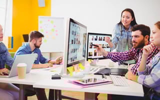 Businessman showing computer screen to coworkers in creative office