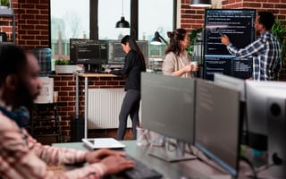 Software developers standing near vertical screen talking about interface bug and slow rate of processing data.