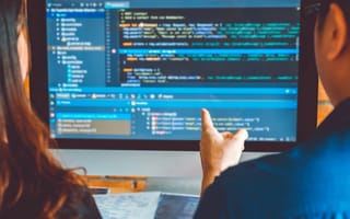 Two software engineers looking at code on a monitor