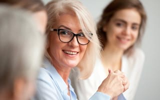 Smiling businesswoman in glasses looking at colleague at team meeting