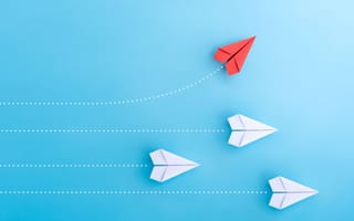 Paper airplanes flying in formation, with one red airplane turning to go higher