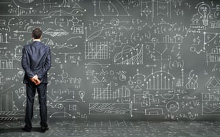 Man standing at chalkboard wall full of graphs and data