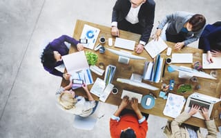 Office workers collaborate at a conference table as seen from above