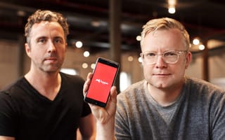Hopper co-founders pose in an office. CTO Joost Ouwerkerk holds a phone with the Hopper logo on the screen.