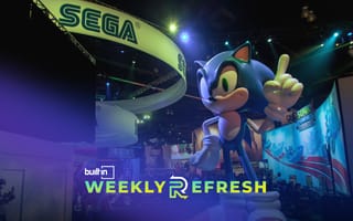 A Sonic the hedgehog at a convention underneath a Sega banner.