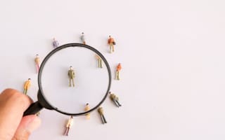 A magnifying glass hovering over small plastic figurines.