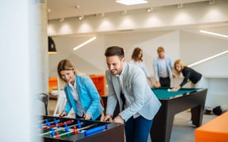 Coworkers playing a foosball table in an office.