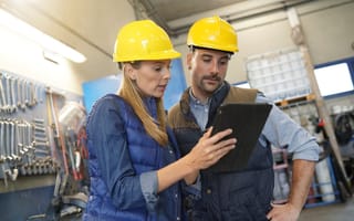 A manager provides instructions to employees using an electronic tablet.
