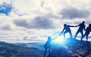 A team helps each other climb a mountain.