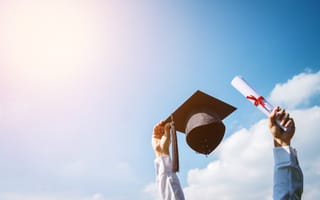 person holding up graduation cap and diploma under sunshine
