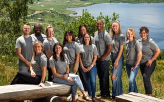 Tilt staff posing for a photo in front of a lake.