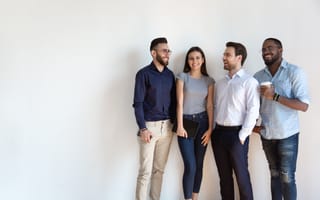 A group of four young businesspeople, talking and smiling.