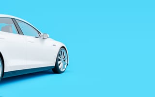 side view of white electric car charging against a bright blue backdrop