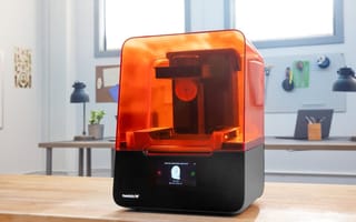 A Star Wars helment that was printed by Formlabs' 3D printer sits on a table next to the printer.