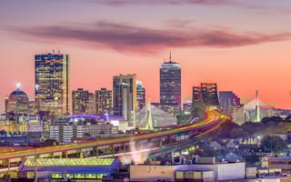 The Boston skyline with bridges and highways at dusk.