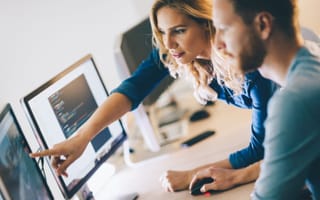 Two software developers look at code together.