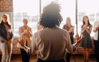 A leader faces four clapping team members.