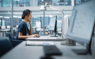 A sales leader sits at her desk smiling.