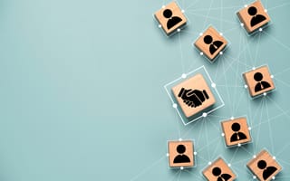 Wooden blocks with icons depicting business partnerships and deal-making.