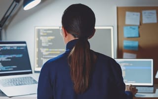 woman sitting in front of several computer monitors