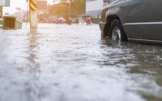 A car drives through a flooded street.