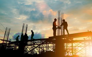 Construction workers are pictured on scaffolding.