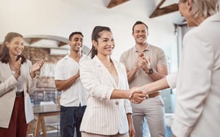 Three clapping coworkers and new hire handshake