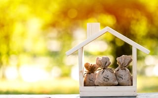A small house full of money bags is pictured.