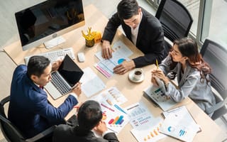 Office workers are shown chatting at a meeting table.