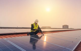 A person works on solar panels atop a roof.