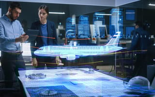 Two aerospace engineers overserve a hologram of an airplane.