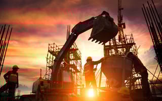 Silhouette Teams of Business Engineers looking for blueprints in construction sites through blurry construction sites at sunset.
