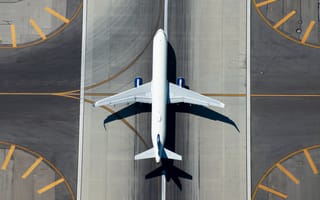 An aerial view of a passenger airplane sitting on an airport runway.