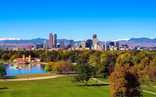 City skyline of Denver Colorado downtown with snowy Rocky Mountains and the City Park Lake.
