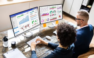 Two employees analyze finance metrics.